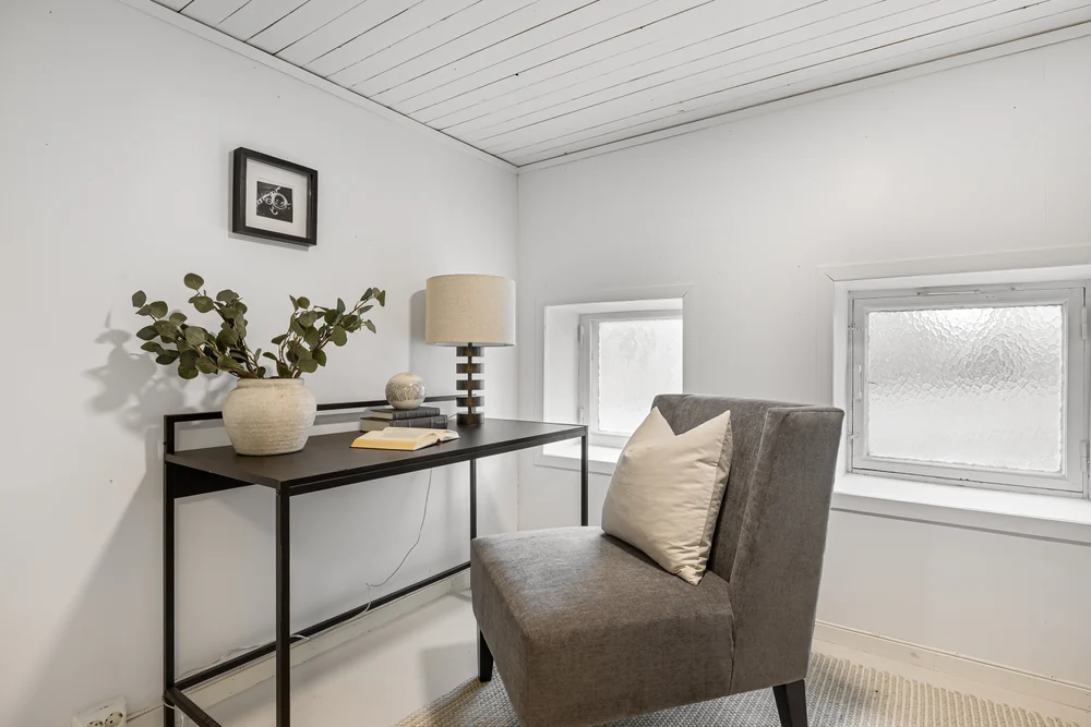 Arbeidsplass med sort skrivebord og grå lenestol.